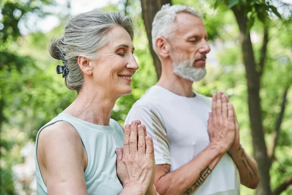 Rentner trainieren und stehen mit Gebetsgeste und fühlen sich dabei so entspannt — Stockfoto