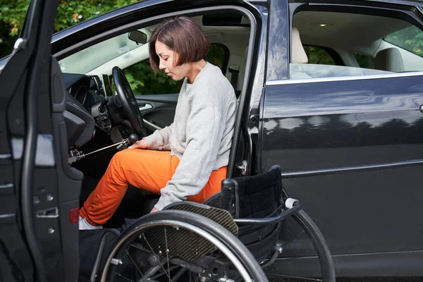 Femme handicapée assise en fauteuil roulant embarquant dans sa voiture — Photo