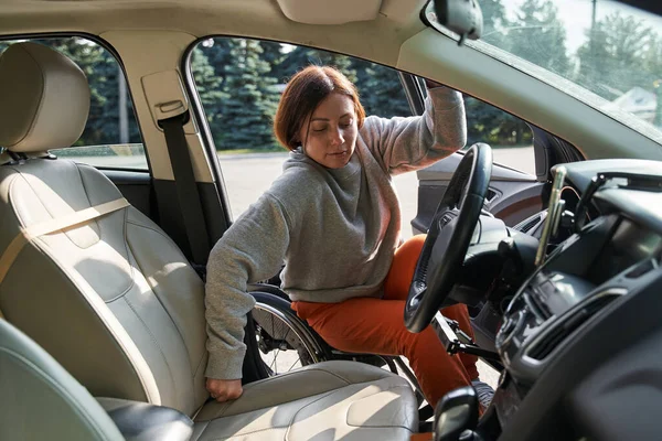 Woman in wheelchair getting into the car on city street and preparing to the traveling — Fotografia de Stock