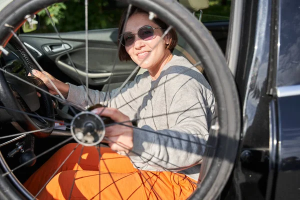 Woman wearing sunglasses folding her wheelchair into the car and smiling to the camera — Φωτογραφία Αρχείου