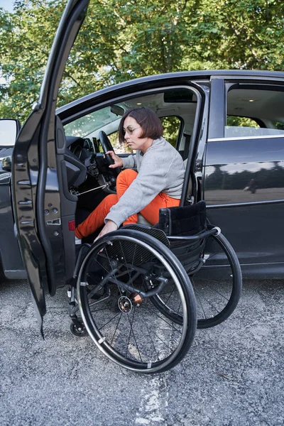 Femme en fauteuil roulant monter sur la voiture aux conducteurs s'asseoir et se préparer à la route — Photo