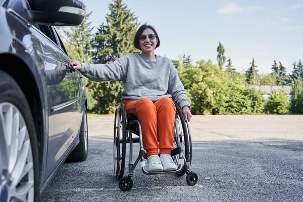 Femme handicapée en fauteuil roulant embarquant sur une porte de voiture pendant la journée ensoleillée — Photo