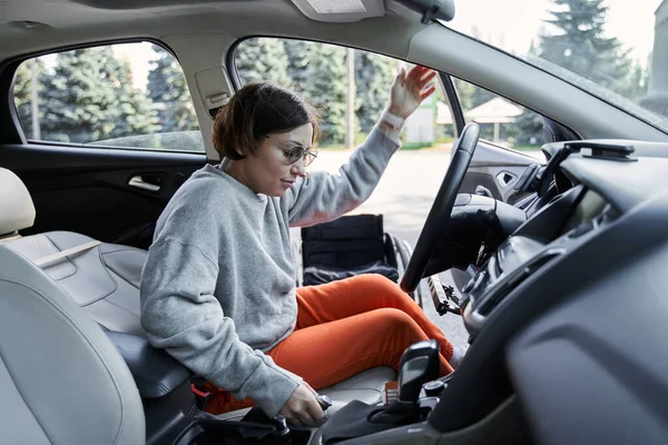 Chica con pérdida de la función de la pierna sentado en el coche en el espacio de estacionamiento para personas con discapacidad — Foto de Stock