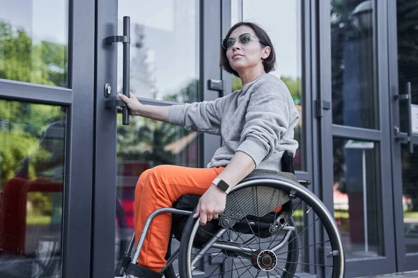Fille handicapée physique se déplaçant au fauteuil roulant et ouvrant les portes — Photo