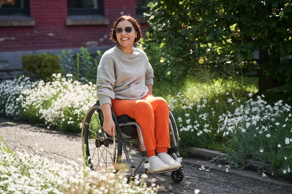 Woman with lower body disability smiling toothy while sitting at the wheelchair