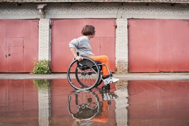 Woman with lower body disability feeling great and moving herself through the puddles