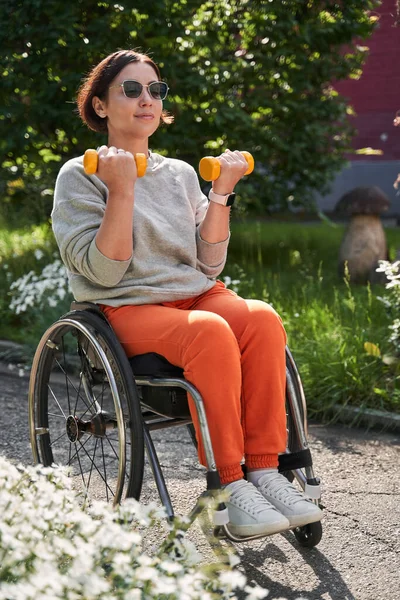 Fille avec perte de la fonction de la jambe assis au fauteuil roulant et ayant l'entraînement avec haltères — Photo