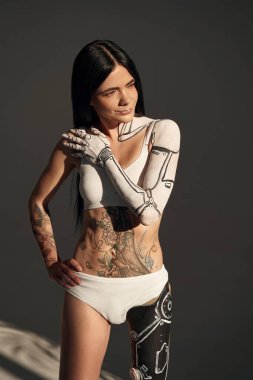 Vücudunda siborg desenli dövmeli kadının dikey görüntüsü stüdyoda koyu arka planda poz veriyor. İnsanlar ve robot konsepti