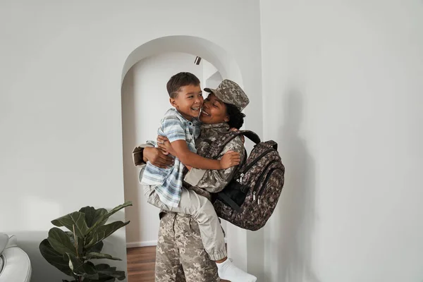 Жінка-солдат сміється і тримає сина за руки після повернення додому — стокове фото