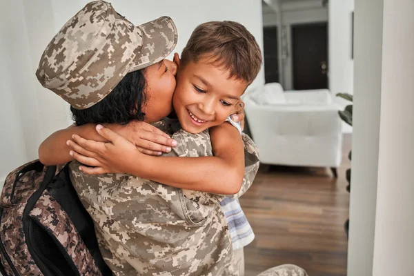 Multiracial kärleksfull mamma återvänder hem till sitt barn och kysser honom med ömhet — Stockfoto