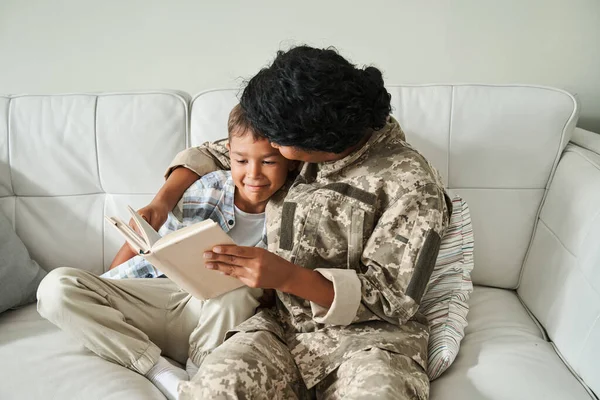 Хлопчик обіймається зі своєю матір'ю і читає книгу разом — стокове фото