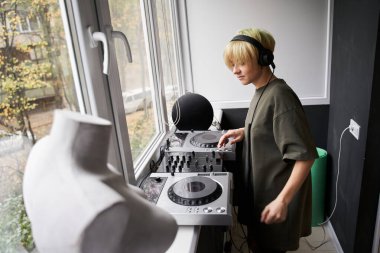 Kadın pencere eşiğinde Midi kontrolörüyle dikiliyor.