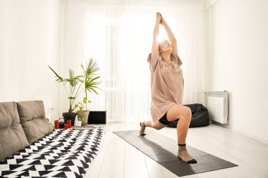 Kadın savaşçı pozunda yoga yapıyor.