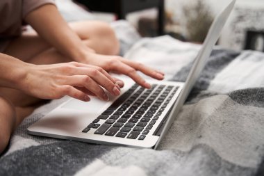 Kadın e-posta yazarken rahat bir yatakta oturuyor