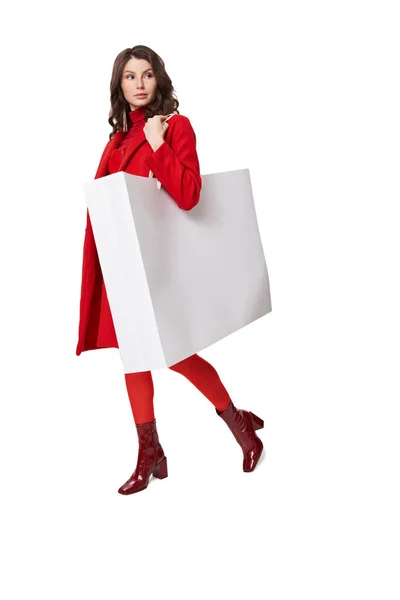 Frau in rotem Mantel steht mit Einkaufstasche im Atelier — Stockfoto