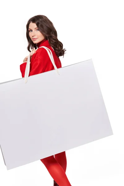 Nő piros kabátban áll bevásárló táska a stúdióban — Stock Fotó