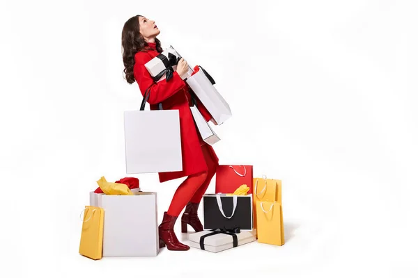 Mujer mirando hacia arriba mientras sostiene un montón de compras — Foto de Stock