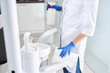 Ciddi doktor dişçi ekipmanlarını temizler ve ofisi hazırlar.
