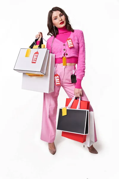 Mujer mirando a la cámara mientras sostiene bolsas de compras — Foto de Stock