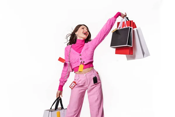 Woman waving with bags and looking up with toothy smile — Stock Photo, Image