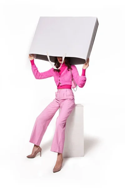 Donna in abiti rosa in piedi con shopping bag alla testa — Foto Stock