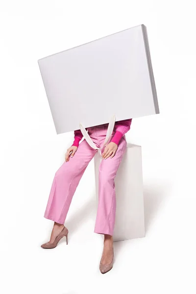 Egy nő bevásárlószatyrot tart a fejéhez a stúdióban. — Stock Fotó