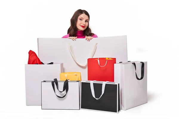 Meisje zit achter boodschappentassen op witte achtergrond — Stockfoto