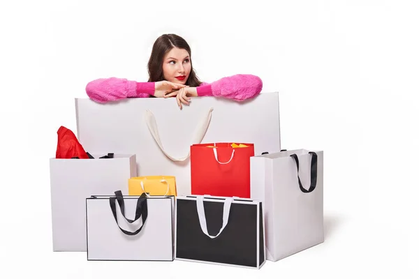 Vrouw zittend achter boodschappentassen op witte achtergrond — Stockfoto