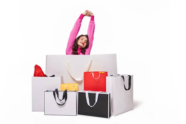 Mujer estirándose con los ojos cerrados mientras está sentada detrás de bolsas de compras —  Fotos de Stock