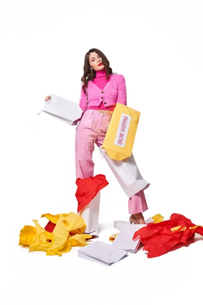 Shopaholic in piedi allo studio e in possesso di sacchetti di carta vuoti — Foto Stock