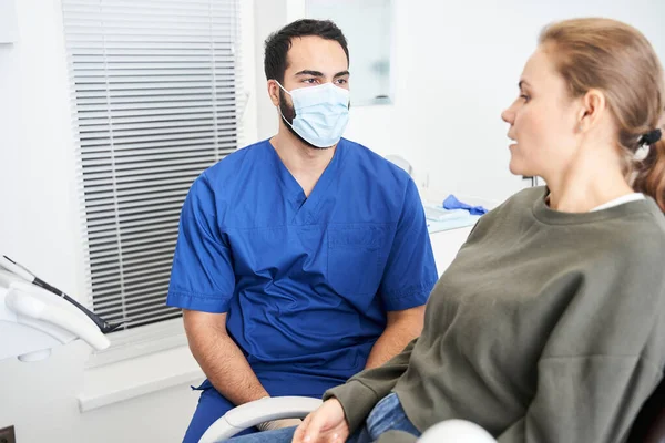 Visão do retrato do dentista masculino em consultório odontológico conversando com paciente do sexo feminino — Fotografia de Stock