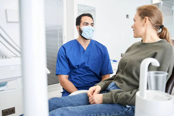 Senhora caucasiana grave na cadeira do dentista pedindo algo para seu médico — Fotografia de Stock