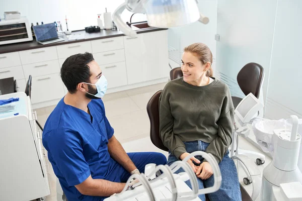 Pohled shora na multiraciálního zubaře a jeho blonďatou pacientku — Stock fotografie