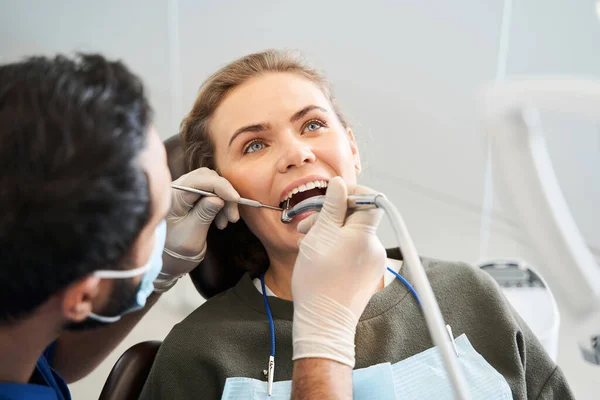 Mujer rubia sonriente que tiene sus dientes examinados por hábil dentista — Foto de Stock