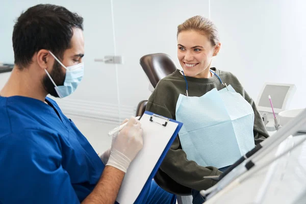 Dentista masculino grave conversando com paciente na clínica odontológica — Fotografia de Stock