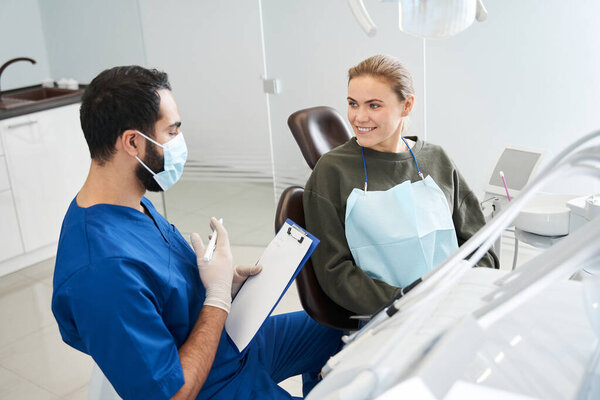 Male dentist showing the paper to a smiling woman client