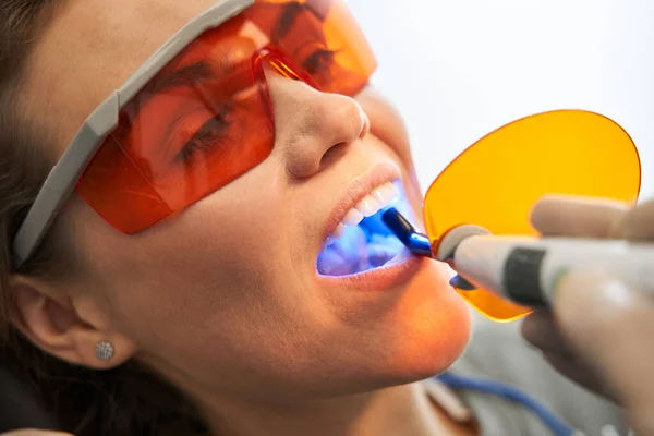 Dentista usando la lámpara UV de curado dental en los dientes del paciente —  Fotos de Stock