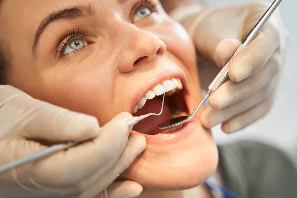 Dama de pelo rubio que tiene sus dientes examinados por un médico serio — Foto de Stock