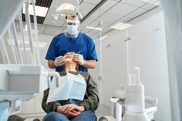 Dentista examinando dentes de sua cliente loira — Fotografia de Stock