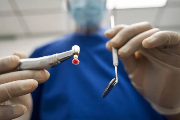 Medico dentista in possesso di strumenti e strumenti mentre in piedi sul lavoro — Foto Stock