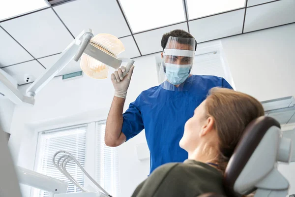 Dentista masculino grave que trabalha na clínica dentária com paciente do sexo feminino — Fotografia de Stock