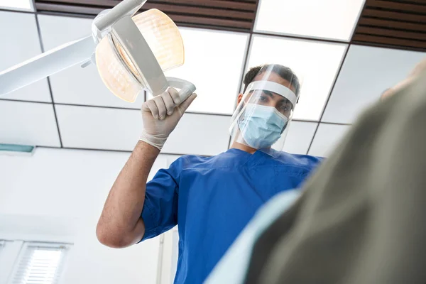 Dentista amigável usando máscara protetora está tratando paciente mulher — Fotografia de Stock