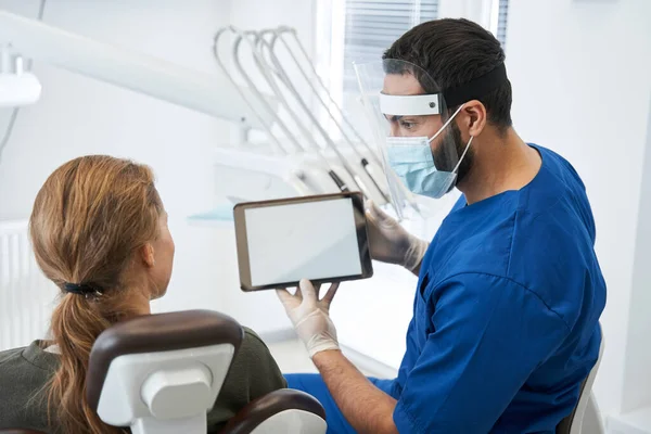 Hombre dentista hablando con su paciente mujer en cirugía dentista — Foto de Stock