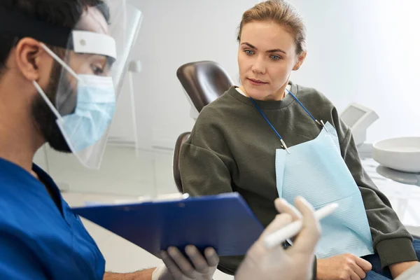 Dentista mostrando el papel a una cliente satisfecha —  Fotos de Stock