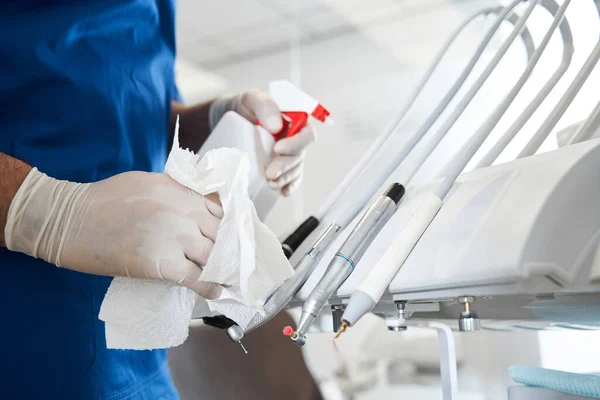 Dentista que usa desinfectante antiséptico, mientras limpia el equipo estomatológico — Foto de Stock
