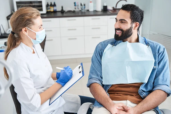 Dentista femenina seria hablando con un paciente en una clínica dental —  Fotos de Stock