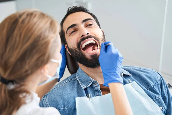 Guapo caucásico hombre sentado en sillón en la oficina del dentista —  Fotos de Stock