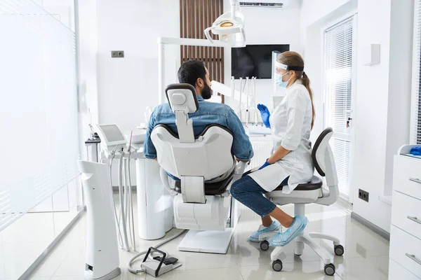 Стоматолог розмовляє з пацієнтом і готується до лікування — стокове фото