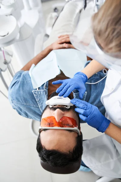 Dentista blanqueamiento de dientes de hombre barbudo sentado en silla dental — Foto de Stock