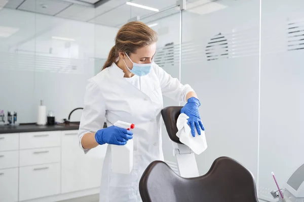 Dentista usando desinfetante anti-séptico e limpeza poltrona estomatologia — Fotografia de Stock